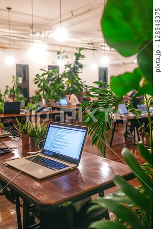 A laptop is on a wooden table in a room with many potted plants 128548375