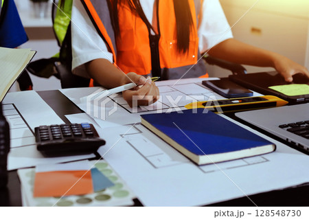 Closeup of team of industrial engineers meeting analyze machinery blueprints consult project on table in manufacturing factory. Working in manufacturing plant or production plant. Closeup of team of industrial engineers meeting analyze machinery blueprints consult project on table in manufacturing factory. Working in manufacturing plant or production plant. 128548730