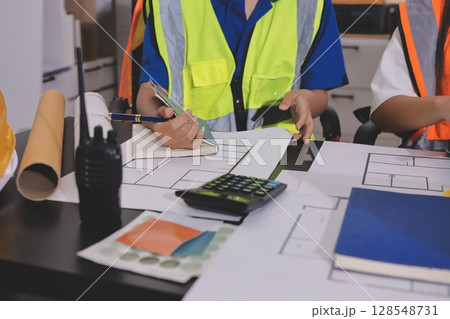 Closeup of team of industrial engineers meeting analyze machinery blueprints consult project on table in manufacturing factory. Working in manufacturing plant or production plant. 128548731