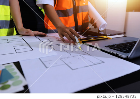Closeup of team of industrial engineers meeting analyze machinery blueprints consult project on table in manufacturing factory. Working in manufacturing plant or production plant. Closeup of team of industrial engineers meeting analyze machinery blueprints consult project on table in manufacturing factory. Working in manufacturing plant or production plant. 128548735