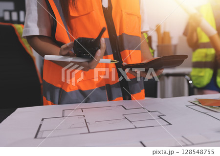 Closeup of team of industrial engineers meeting analyze machinery blueprints consult project on table in manufacturing factory. Working in manufacturing plant or production plant. Closeup of team of industrial engineers meeting analyze machinery blueprints consult project on table in manufacturing factory. Working in manufacturing plant or production plant. 128548755