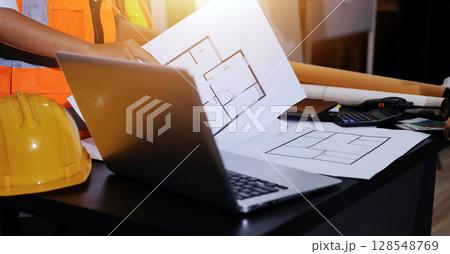 Closeup of team of industrial engineers meeting analyze machinery blueprints consult project on table in manufacturing factory. Working in manufacturing plant or production plant. Closeup of team of industrial engineers meeting analyze machinery blueprints consult project on table in manufacturing factory. Working in manufacturing plant or production plant. 128548769