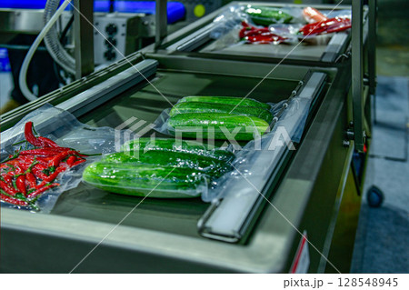 Fresh vegetables packed in a clear plastic wrap production line in factory, industrial food production Fresh vegetables packed in a clear plastic wrap production line in factory, industrial food production 128548945