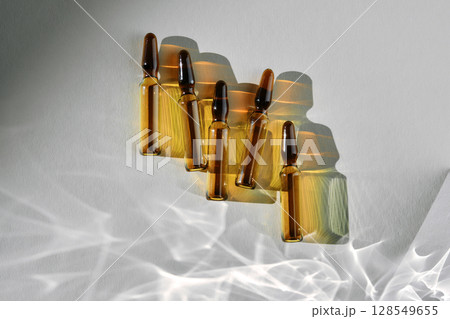 Ampoules on a gray background with stripes of shadows. 128549655