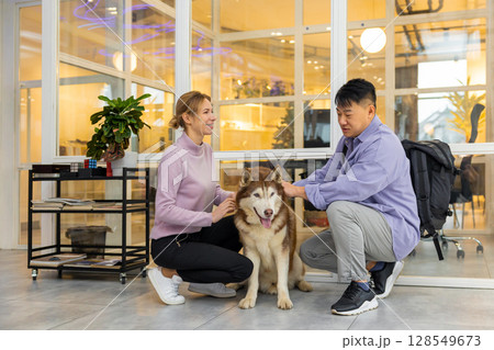 Two colleagues in a coworking area with a dog Two colleagues in a coworking area with a dog 128549673