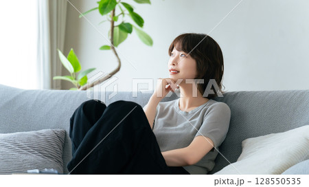 リビングのソファに座る笑顔の女性 リビングのソファに座る笑顔の女性 128550535