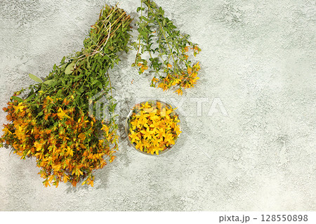 Bouquet of St. John's wort on a concrete table for collecting useful herbs and treatment according to folk recipes, Medicinal herbal tea, concept of alternative folk medicine, advertising of a green 128550898
