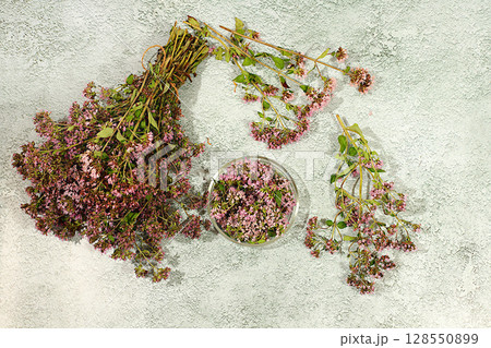 Bouquet of oregano and petals in a glass cup on a concrete table for collecting useful herbs and treatment according to folk recipes, Medicinal herbal tea, concept of alternative folk medicine, Bouquet of oregano and petals in a glass cup on a concrete table for collecting useful herbs and treatment according to folk recipes, Medicinal herbal tea, concept of alternative folk medicine, 128550899
