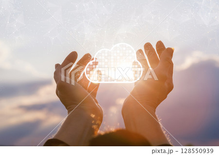 Hands holding a cloud symbol against the sunset 128550939