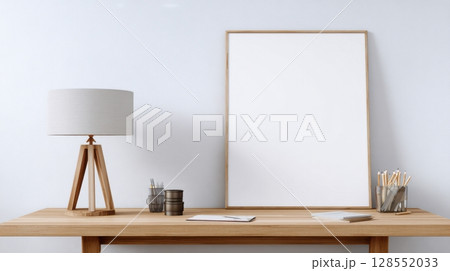 Modern wooden shelf with desk lamp and stationery in a minimalist room. White wall background perfect for showcasing artwork or poster mockups. 128552033