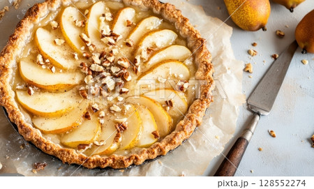 Rustic pear and goat cheese pie topped with nuts and golden edges, styled on parchment with cozy artisan details and warm natural lighting. Rustic pear and goat cheese pie topped with nuts and golden edges, styled on parchment with cozy artisan details and warm natural lighting. 128552274