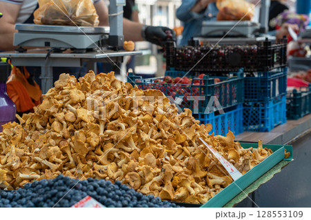Large heap of golden chanterelle mushrooms on a market. Close-up of many chanterelle fungi. Harvested edible yellow forest mushrooms 128553109