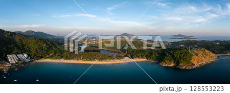 Aerial view of Naiharn Beach in Phuket, Thailand, featuring a crescent shoreline, lush green hills, a lagoon, white buildings, and distant islands. Aerial view of Naiharn Beach in Phuket, Thailand, featuring a crescent shoreline, lush green hills, a lagoon, white buildings, and distant islands. 128553223