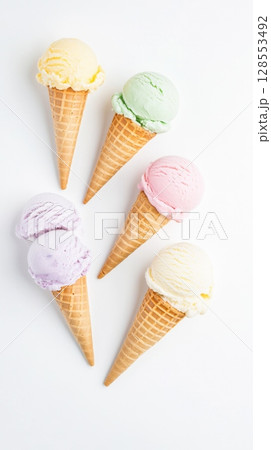 Top view of five mini pastel ice cream cones in a diagonal row, each scoop in a different flavor. Bright, creamy textures perfect for summer ads, packaging, and dessert visuals. 128553492