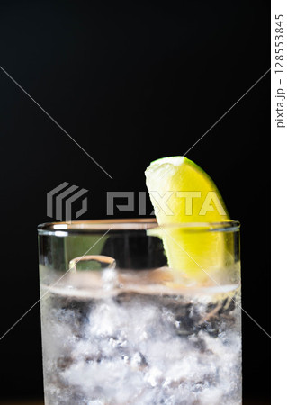 【カクテル素材】氷の入ったグラスに注がれた美味しそうなジントニック・黒バック【ドリンク素材】 128553845