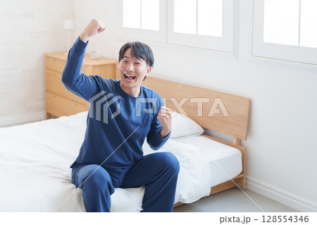 ベッドでガッツポーズする男性 128554346