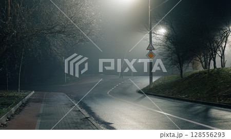 Empty Curved Road at Night with Fog and Streetlights Empty Curved Road at Night with Fog and Streetlights 128556293