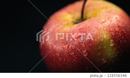 Artistic macro of a ripe apple surface, glistening with dew - a symbol of natural beauty and desire. 128556346