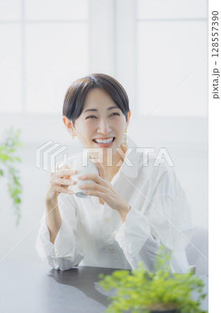 リビングでコーヒーを飲むミドルの女性 リビングでコーヒーを飲むミドルの女性 128557390