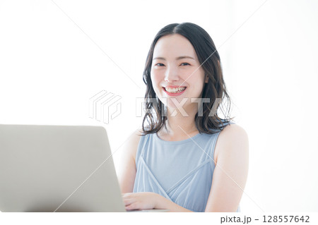 パソコンの前のかわいいカメラ目線の女性　春夏のノースリーブ白バック ワンピースの水色 128557642