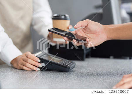 Contactless Mobile Payment at a Modern Retail Store Counter with Coffee in Background 128558067