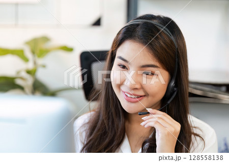 Friendly Female Customer Service Representative with Headset Working in Modern Office Environment 128558138
