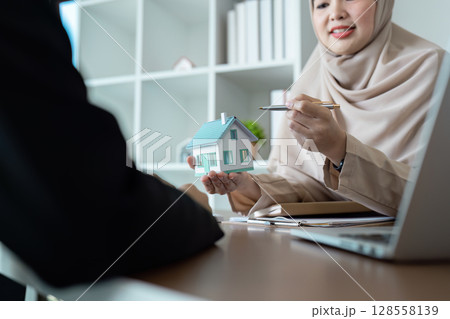 Real Estate Agent Discussing Property Sale with Client in Modern Office Setting Real Estate Agent Discussing Property Sale with Client in Modern Office Setting 128558139