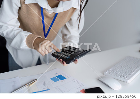 Business Professional Calculating Financial Data with Calculator at Office Desk for Accurate Budget Planning Business Professional Calculating Financial Data with Calculator at Office Desk for Accurate Budget Planning 128558450