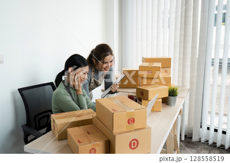 Small Business Owners Working on E-commerce Orders in a Modern Office Setting Small Business Owners Working on E-commerce Orders in a Modern Office Setting 128558519