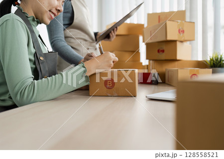 Small Business Owners Preparing Packages for Shipment in Modern Office Setting 128558521