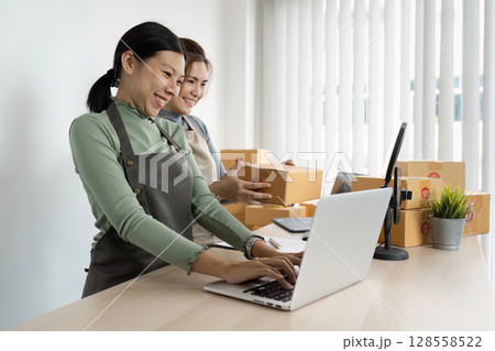 Small Business Owners Working Together in Modern Office with Laptop and Packages 128558522