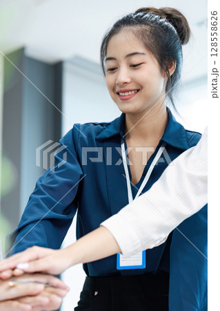 Smiling Businesswoman Collaborating with Colleagues in Modern Office Environment Smiling Businesswoman Collaborating with Colleagues in Modern Office Environment 128558626