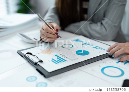 Business Professionals Analyzing Financial Data and Charts in a Modern Office Environment 128558706