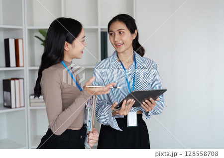 Professional Businesswomen Collaborating in Modern Office Environment with Digital Devices 128558708