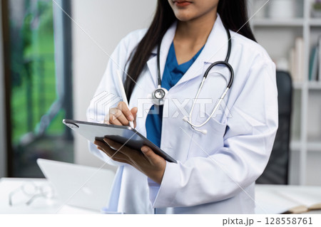 Female Doctor Using Digital Tablet in Modern Medical Office with Stethoscope Around Neck Female Doctor Using Digital Tablet in Modern Medical Office with Stethoscope Around Neck 128558761
