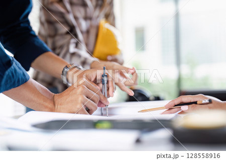 Engineers Collaborating on Project Plans with Technical Drawings and Tools in Office Environment 128558916