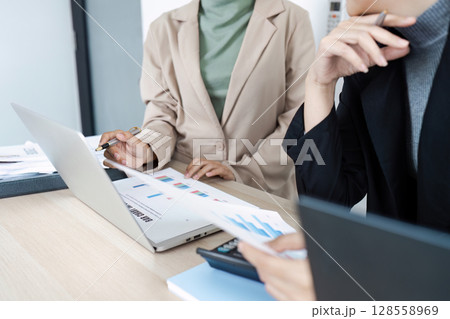 Professional Business Meeting with Colleagues Analyzing Financial Data and Charts on Laptop and Documents Professional Business Meeting with Colleagues Analyzing Financial Data and Charts on Laptop and Documents 128558969