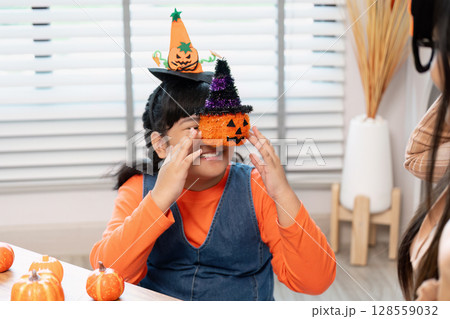 Child Enjoying Halloween Celebration with Pumpkin Hat and Decorations in a Festive Indoor Setting 128559032