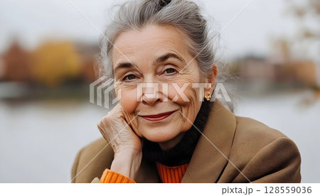 Smiling senior woman portrait gray hair brown coat natural light 128559036