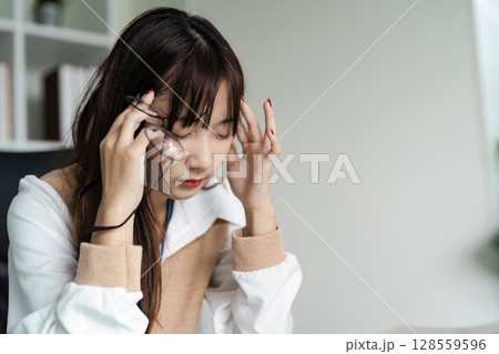 Stressed Office Worker Experiencing Headache Due to Office Syndrome in Modern Workplace Environment 128559596