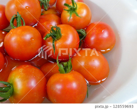 赤く熟した中玉トマトを、水を張った白色のボールで冷やす色あざやかな写真 128559693