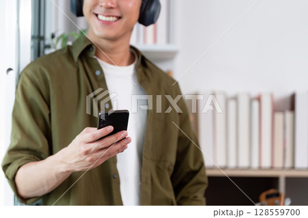 Work from Home: Smiling man checking smartphone while relaxing Work from Home: Smiling man checking smartphone while relaxing 128559700