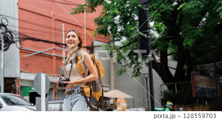 Urban travel. Happy woman exploring city streets with camera in hand. Urban travel. Happy woman exploring city streets with camera in hand. 128559703