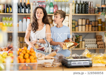 Adolescence boy with mother choose consider snacks in shop 128560058