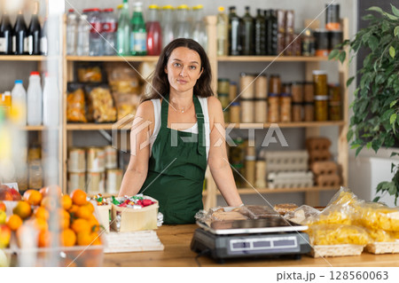 Woman works as salesperson, waiting for customers at store counter 128560063