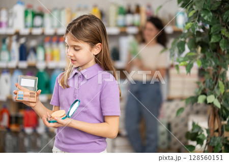 Girl chooses cosmetics in household chemicals store 128560151