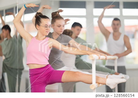 Ballet pose grand batman - girls and boys at a choreography lesson are learning ballet movements in studio 128560154