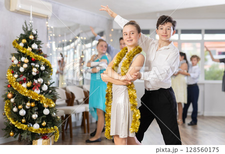 Teenagers in holiday clothes dancing swing dance near Christmas tree Teenagers in holiday clothes dancing swing dance near Christmas tree 128560175