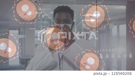 Multiple covid-19 cells moving against portrait of african american male doctor wearing face mask 128560208