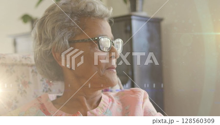 Image of glowing light over serious senior woman wearing reading glasses 128560309
